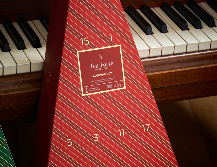 A red triangular Advent Calendar with diagonal stripes and numbered compartments, placed in front of a piano keyboard.
