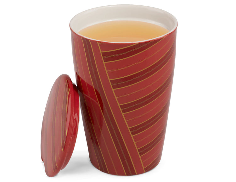Warming Joy KATI Steeping Cup with a matching lid leaning against it, filled with a light amber tea, on a clean white background.
