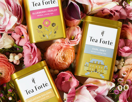 3 loose tea canisters on a bed of flower petals