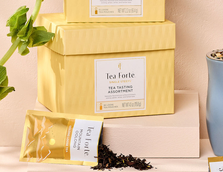 MAIN PDP | Single Steeps tea assortment in a 30count chest of Single Steeps pouches with lid closed and one pouch spilling out tea