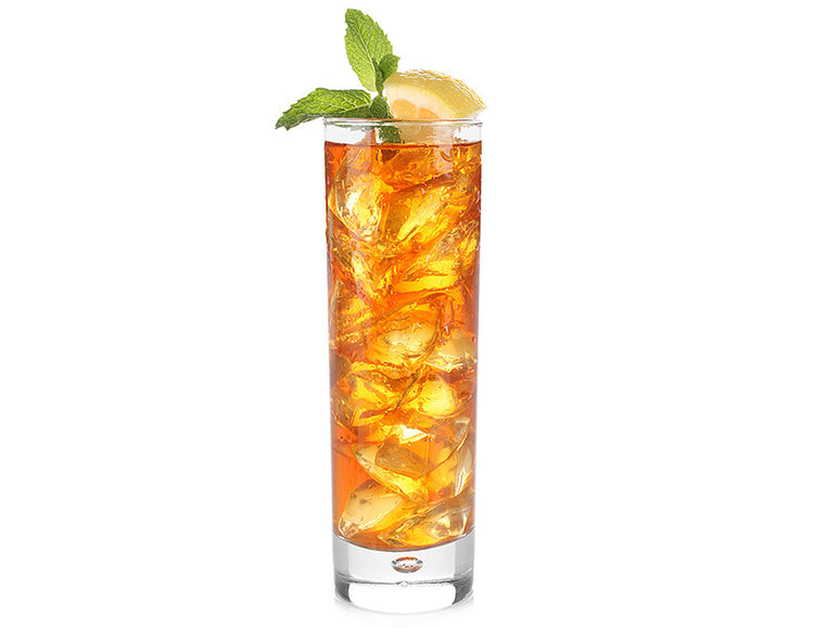 A tall clear glass filled with an Ceylon Gold Iced tea, garnished with a mint leaf and a lemon wedge, isolated on a white background.
