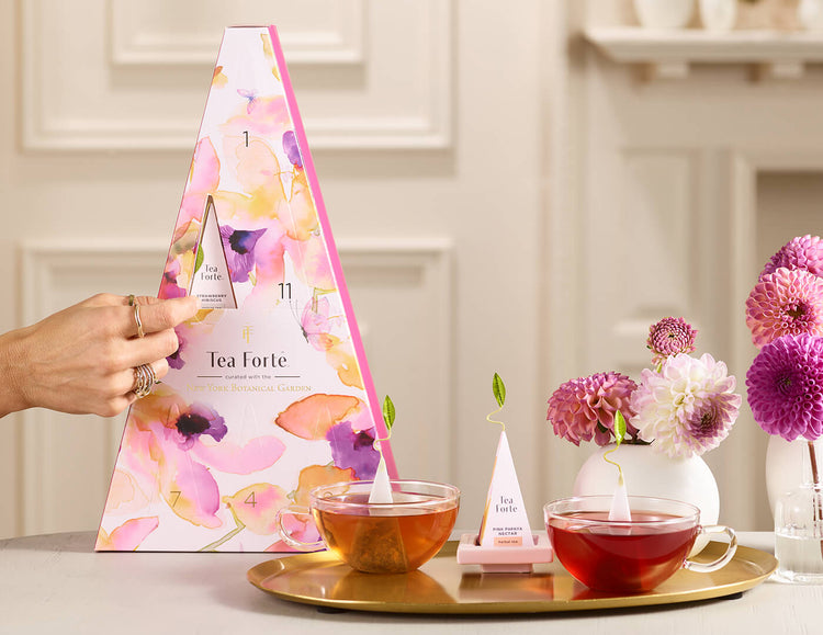 Opening a door of the Mariposa 12 days of Blissful Teas box with teacups and and infuser next to it