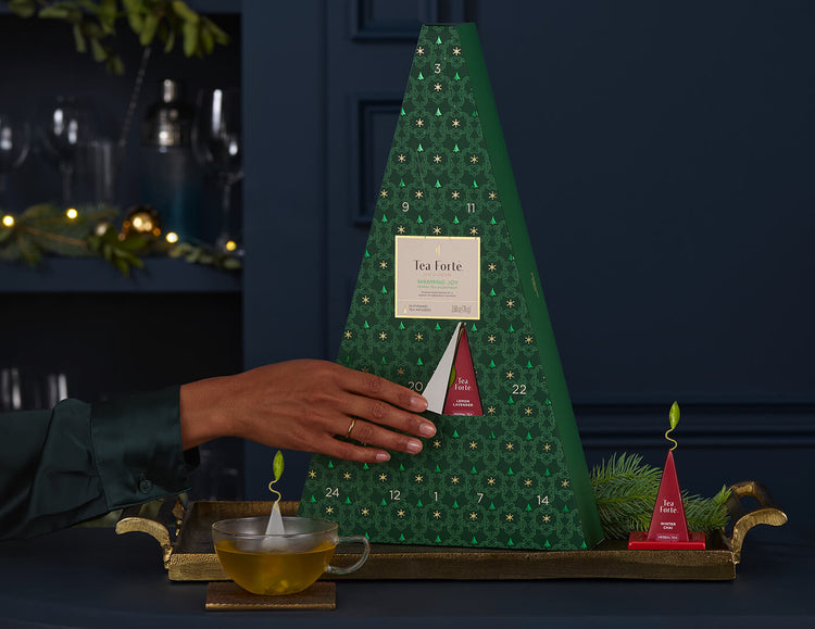 Opening a door of the Warming Joy Herbal Advent Calendar, with cup and tea and infuser on a tray