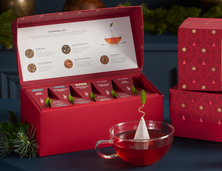 Presentation Box Warming Joy open and a glass cup of tea on a dark blue background