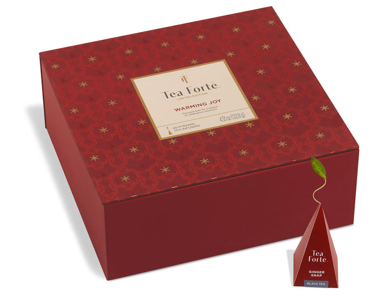 Warming Joy Tea Chest, one wrapped with a ribbon, the other open, with a glass teacup and infuser on a red tray