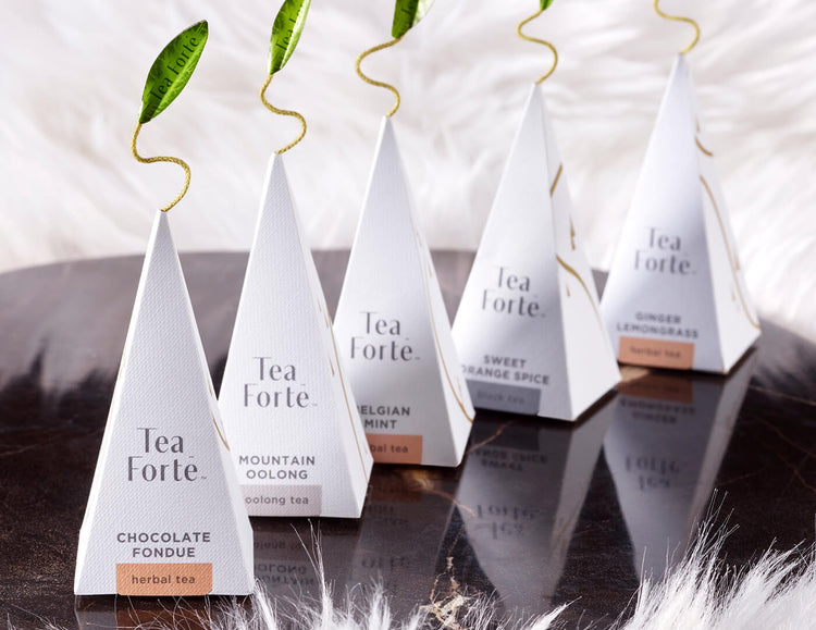 Five Winter Chalet pyramid tea infusers on a mirror surrounded by white fur