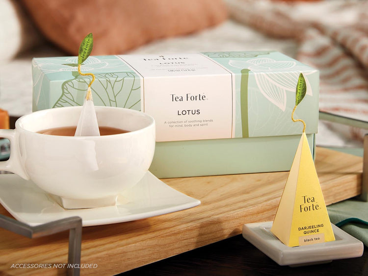 Lotus Presentation Box of 20 pyramid tea infusers on a table with a white cup of tea and pyramid infuser on a tray